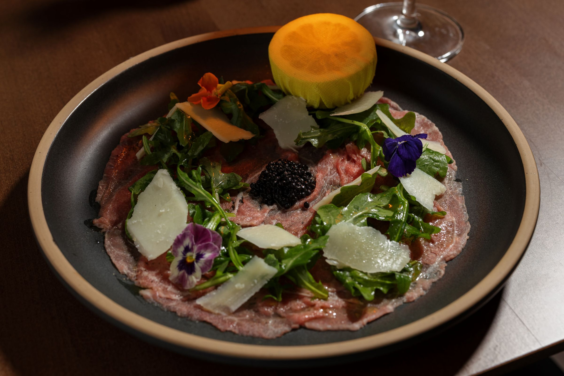 Thin-sliced beef carpaccio with arugula, Parmigiano, caviar, and lemon